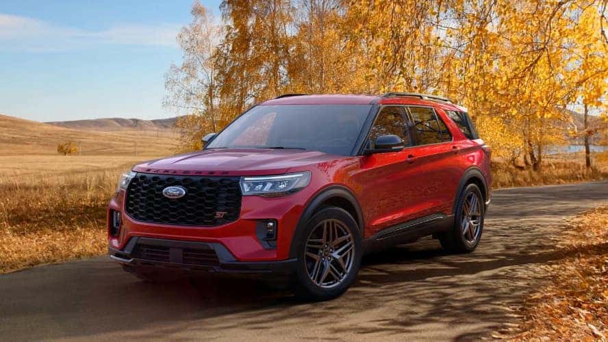 A red Ford Explorer driving down the road in autumn.