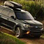 A black Ford Expedition driving down a dirt road.