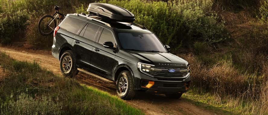 A black Ford Expedition driving down a dirt road.
