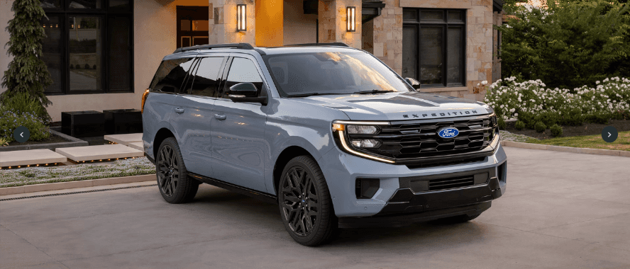 A metallic gray-blue Ford Expedition parked in front of a house.