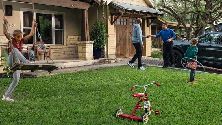 two people in driveway with kids playing