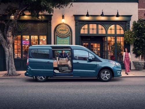 2023 Ford Transit Connect parked with doors open and man loading things inside