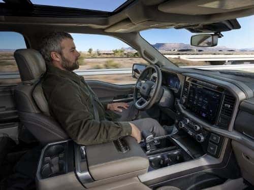 2024 Ford F-150 side view of man in driver seat with hands off steering wheel while vehicle is in BlueCruise mode