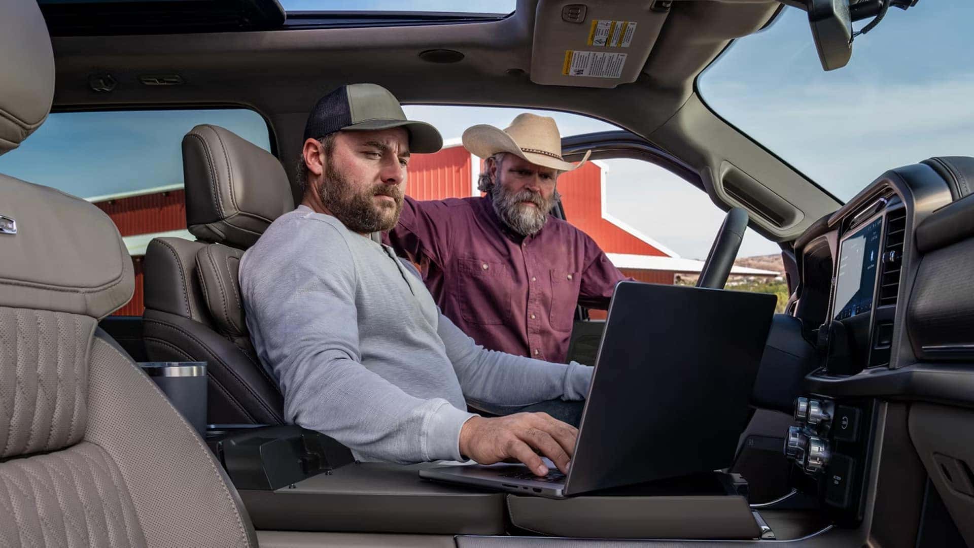 2026 Ford F-150 interior with fold-down work surface and laptop in use, highlighting in-cabin workspace and everyday utility.