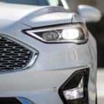 A close up shows the drivers headlight on a white 2020 Ford Fusion.