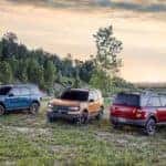 A blue, a yellow, and a red 2021 Ford Bronco Sport are shown parked on the grass.
