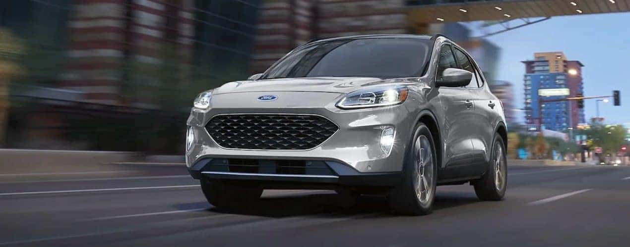 A silver 2021 Ford Escape Hybrid Titanium is shown driving on a city street after 2021 Ford Escape vs 2021 Chevy Equinox battle.